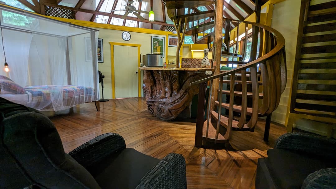 Interior looking across the polished hardwood floor to the spiral wooden staircase rising to the king